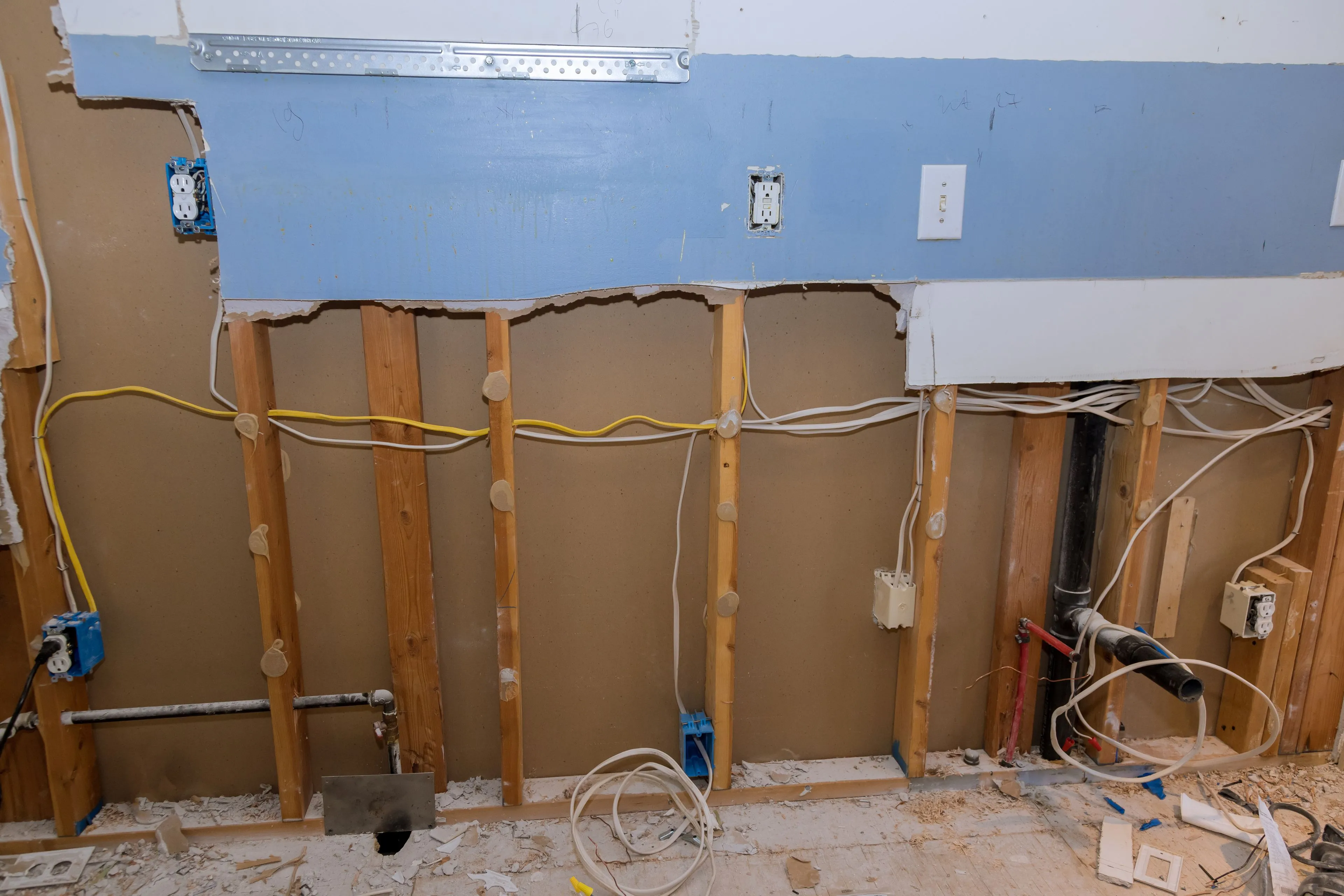 Professional interior selective demolition in a Dallas property showing a carefully stripped wall with exposed wooden studs and electrical wiring ready for renovation.